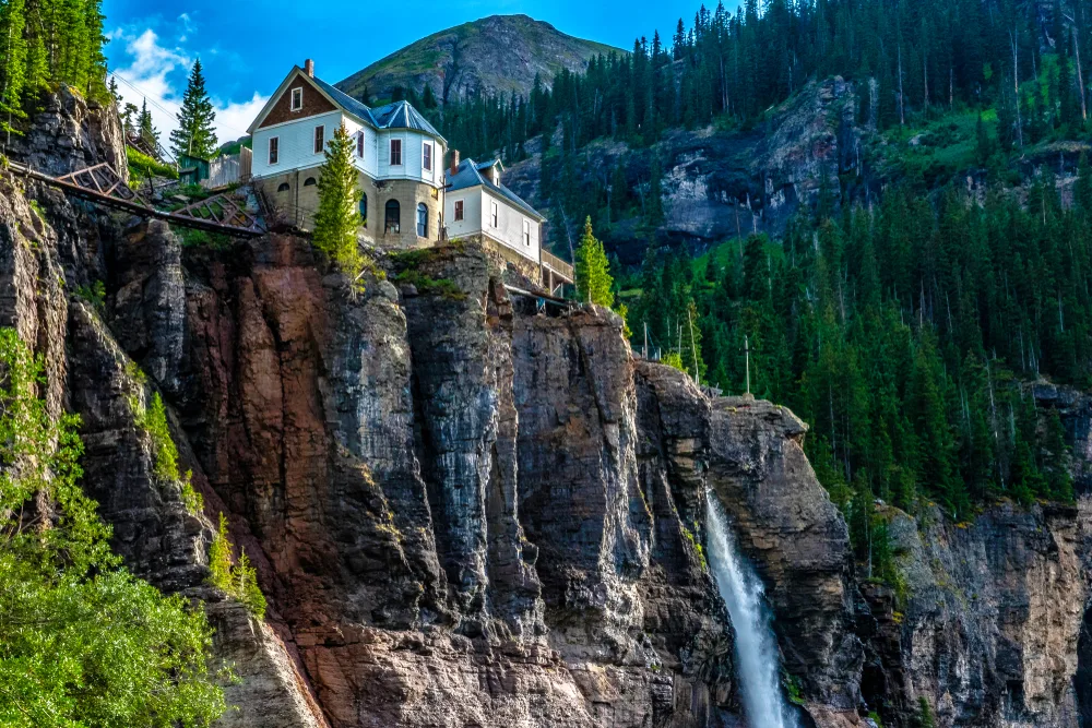 Photo of a house at the top of Bridal Veil Falls pictured during the Spring, the overall least busy time to visit Telluride