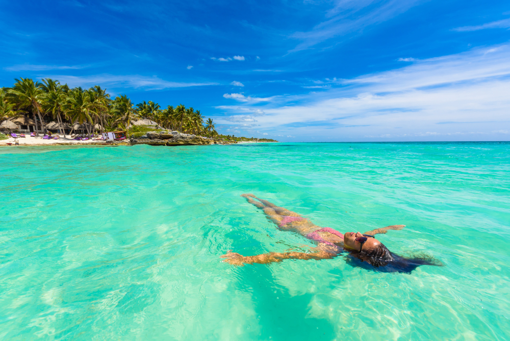 Woman floating on her back in a pink bikini in the gorgeous crystal-clear waters of Riviera Maya, as seen during the best time to visit