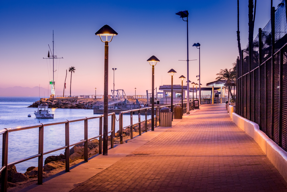 Empty brick walkway to the dock with boats in the bay and a pink sunset overhead pictured in January, the overall least busy time to visit Catalina Island