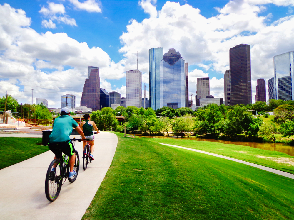 Fit man and woman on bikes making their way through a green park in the middle of downtown during the best time to visit Houston