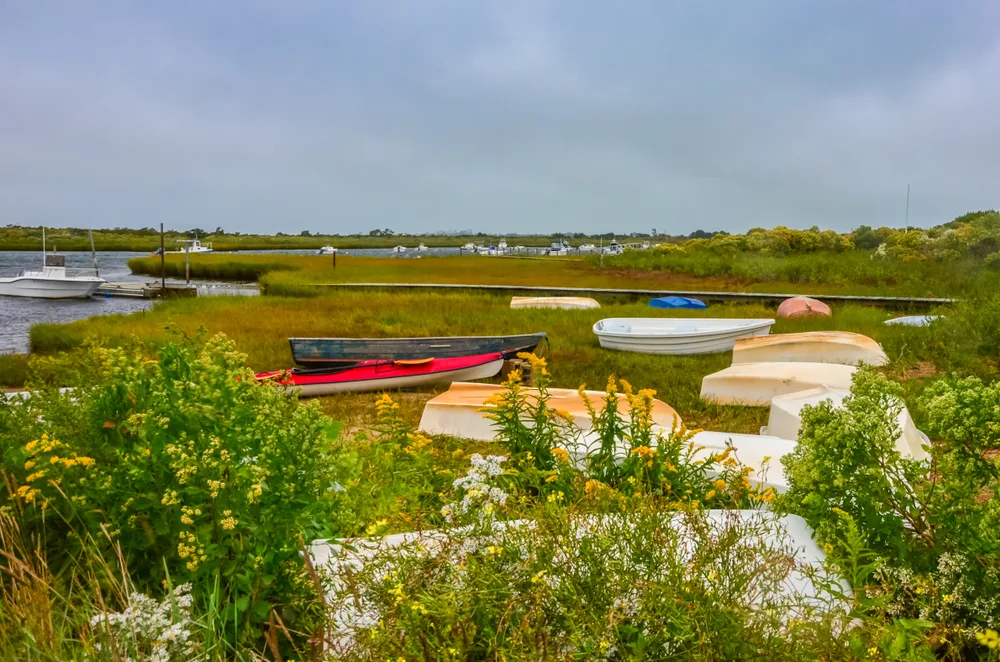 Fishing boats in a dry part of a marsh on a gloomy day during autumn, one of the cheapest times to visit Nantucket