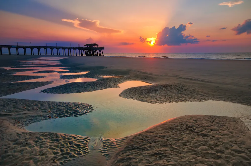 Sunrise on a deserted beach next to the pier during the least busy time to visit Tybee Island
