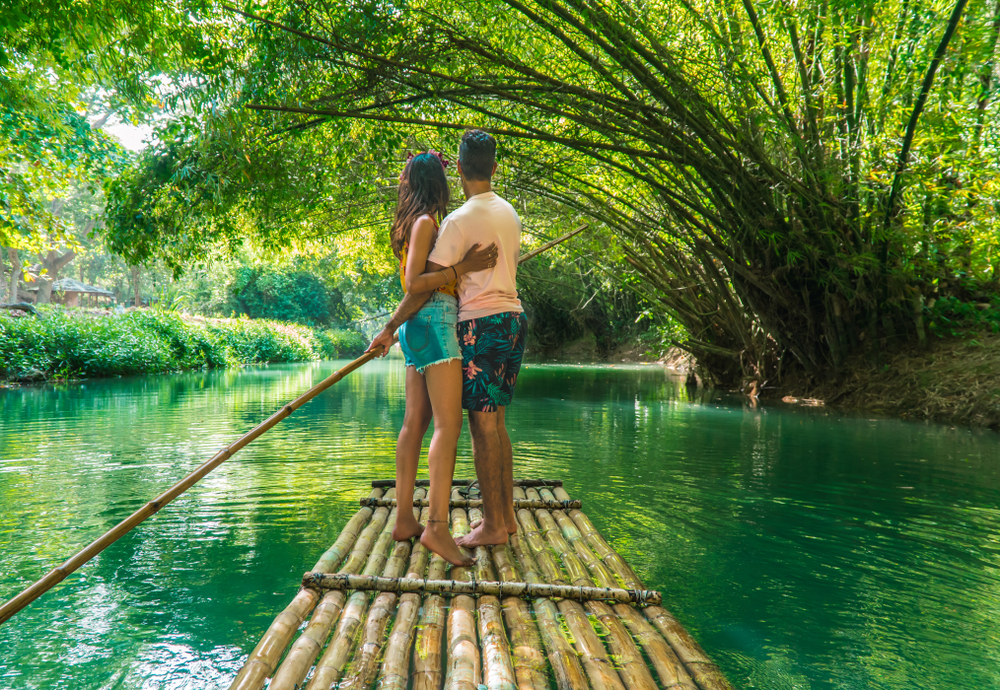 Happy couple floating down a river on a wooden log raft during the best time to go to Montego Bay
