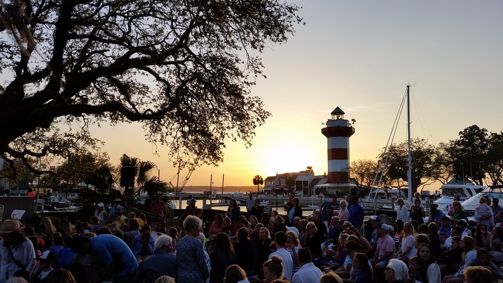 Lots of people crowding a space by the lighthouse during the summer, the worst time to visit Hilton Head