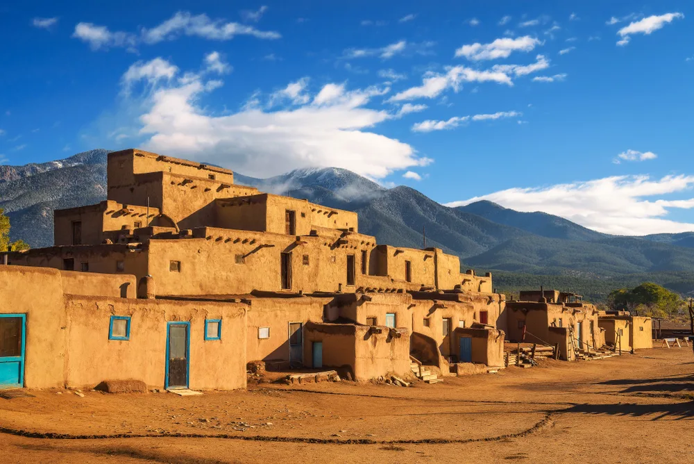 Neat adobe homes of the Taos Pueblos pictured on a blue sky day for a piece on the best places to visit in the Winter in the USA