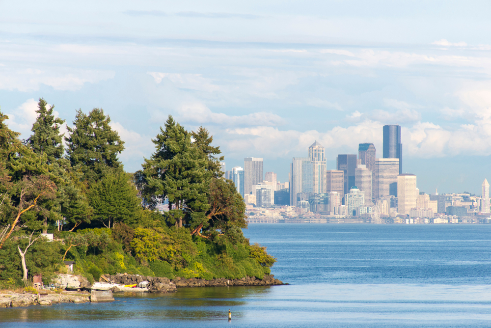 Image of Bainbridge, a great day trip from Seattle, pictured from the shore looking toward trees and downtown Seattle