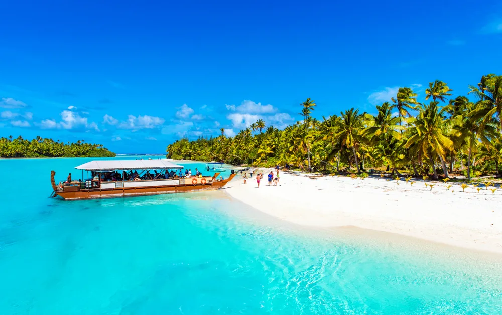 Boat docked on the white sand beach of Aitutaki, pictured during the best time to go to the Cook Islands