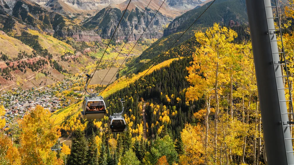 Ski lift pictured in autumn with gorgeous gold and yellow trees pictured during the best time to visit Telluride