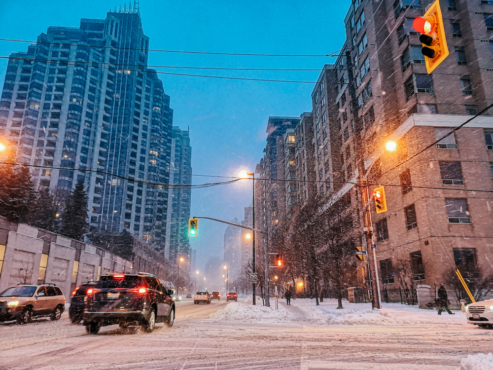Snow falling between buildings during the worst time to visit Toronto, the winter