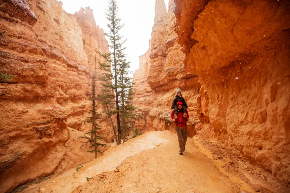 Father and son hiking in between amazing red rock formations during the overall least busy time to visit Bryce Canyon