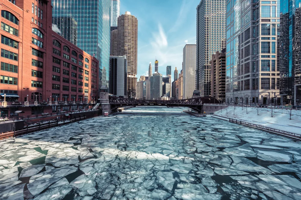 Frozen lake in Chicago, one of the best places to visit in winter in the USA, pictured between buildings by someone standing on a bridge