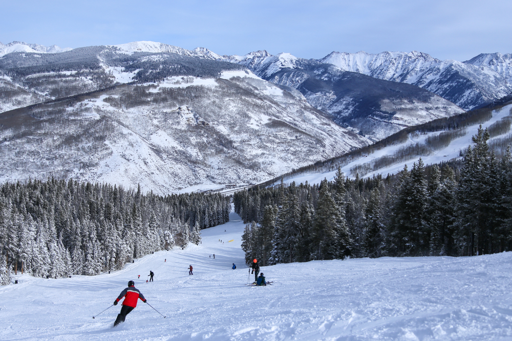 People skiing down a snow-covered hill in Vail on a clear day for a piece on the best places to visit in Winter in the USA