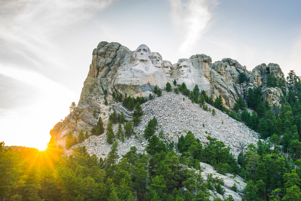 Gorgeous dusk shot of the presidents on the cliff pictured during the best time to visit Mount Rushmore with the sun behind the hills