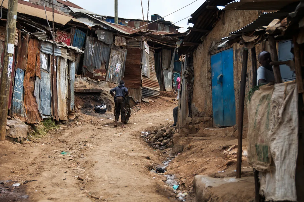 Man walking through the streets of a slum with mud huts for a piece on how to avoid the bad parts of Africa