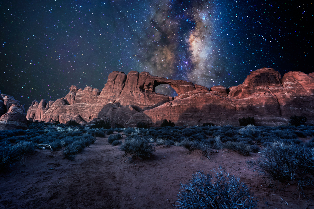 The Milky Way shining brightly over the Window of Arches National Park during the best time to go to Moab