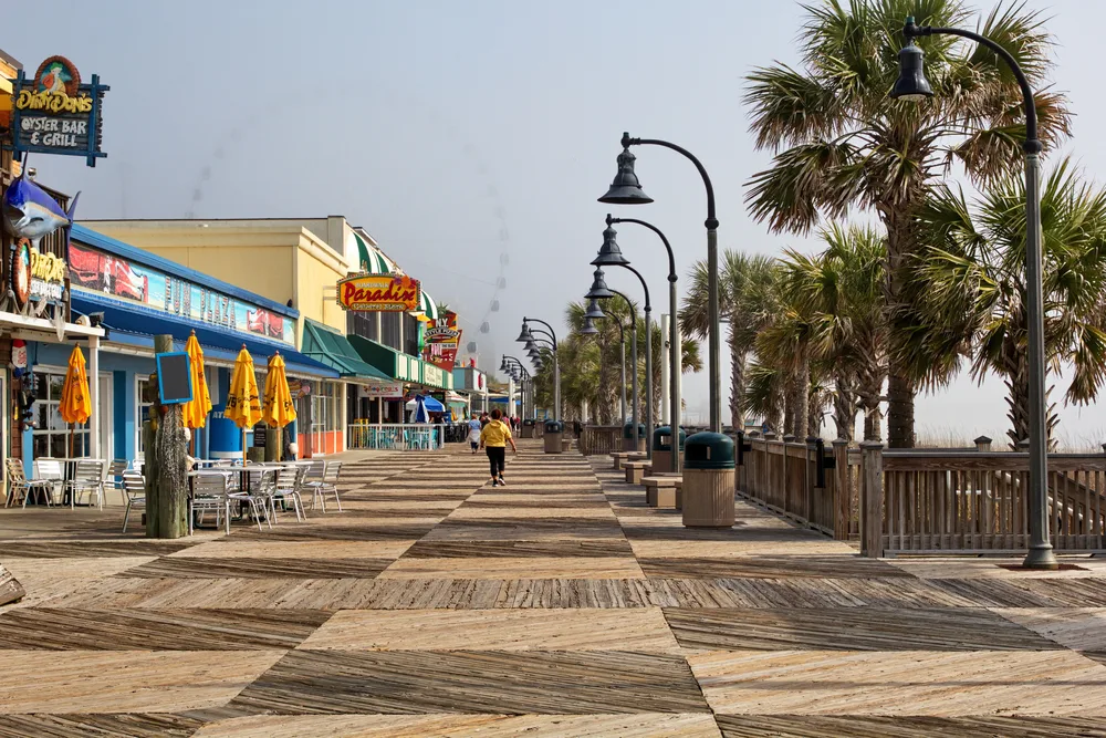 Myrtle Beach boardwalk pictured during the best time to visit South Carolina with palm trees lining the beach