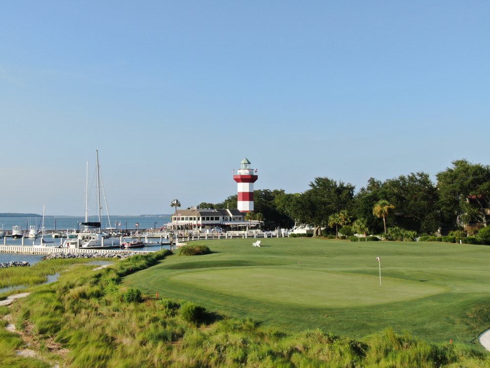 Gorgeous green grass golf course next to the red and white lighthouse pictured during the spring, the best time to visit Hilton Head