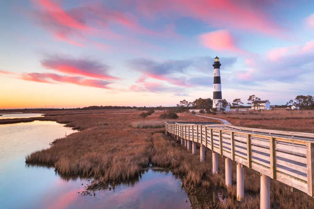 Ribbon-like pink clouds with a lighthouse in the Outer Banks overlooking a marsh