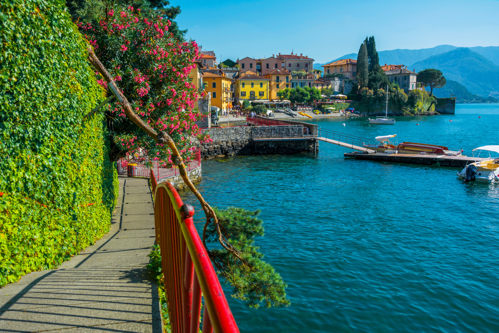 Walkway with a red railing along the water in the old town of Varenna during the best time to go to Lake Como