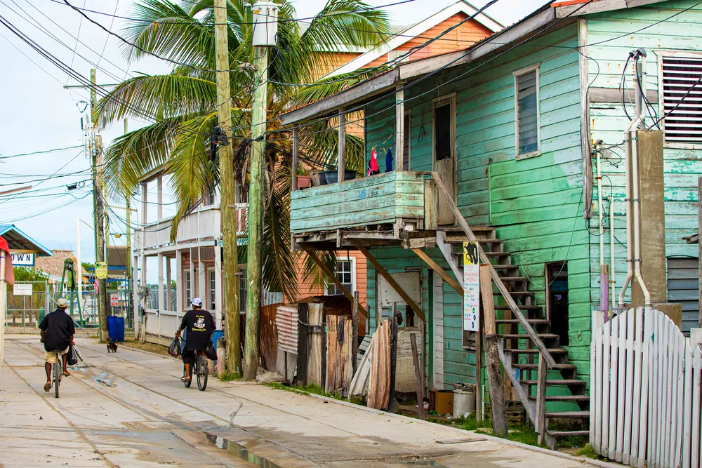 Dilapidated buildings in San Pedro pictured with men walking along the alleyway for a piece titled Is Belize Safe to Visit
