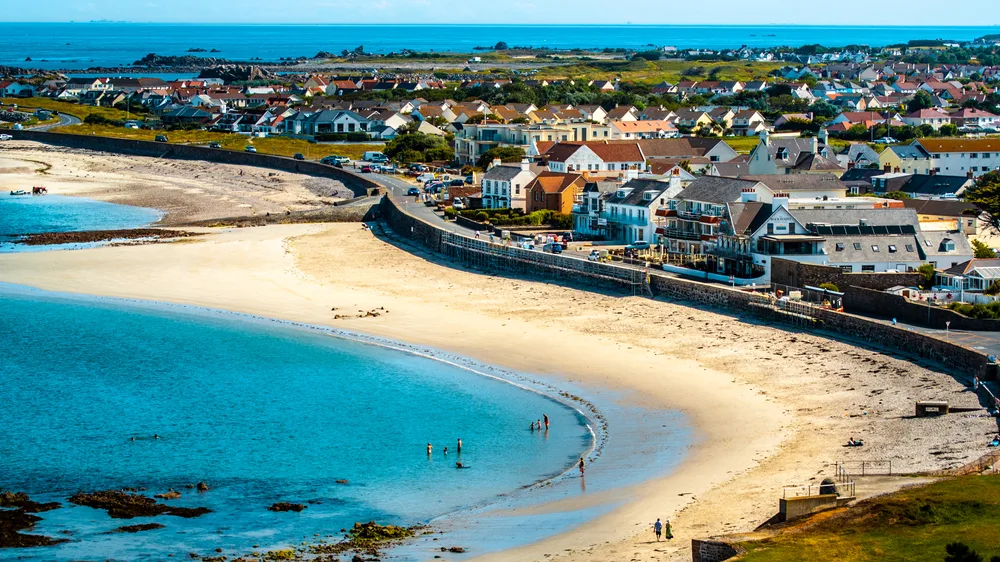 Blue waters and white sand beach pictured form the air at Cobo Bay in Guernsey, one of the best places to visit in the UK