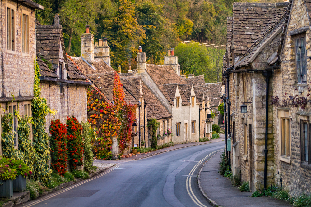 Rural town of Cotswolds with a road winding through the old stone homes for a piece on on the best places to visit in the UK