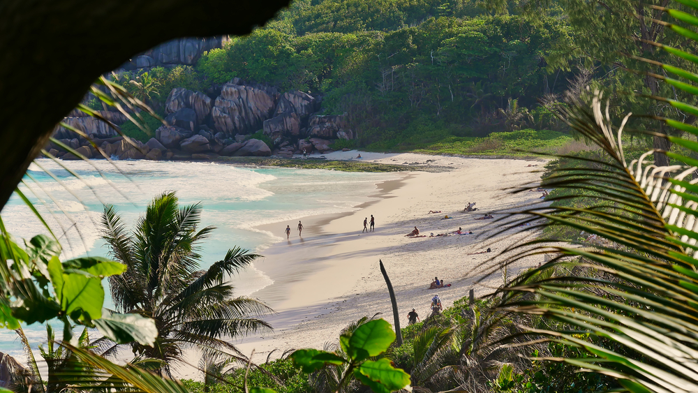 Seychelles beach pictured with rain during the worst time to visit with people sitting in the water