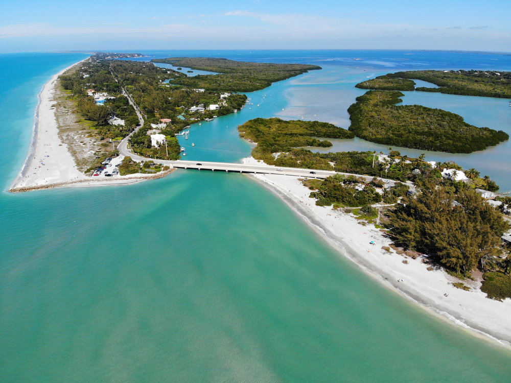Long and expansive white sand beaches running along teal water with vegetation inland pictured during the best time to visit Sanibel