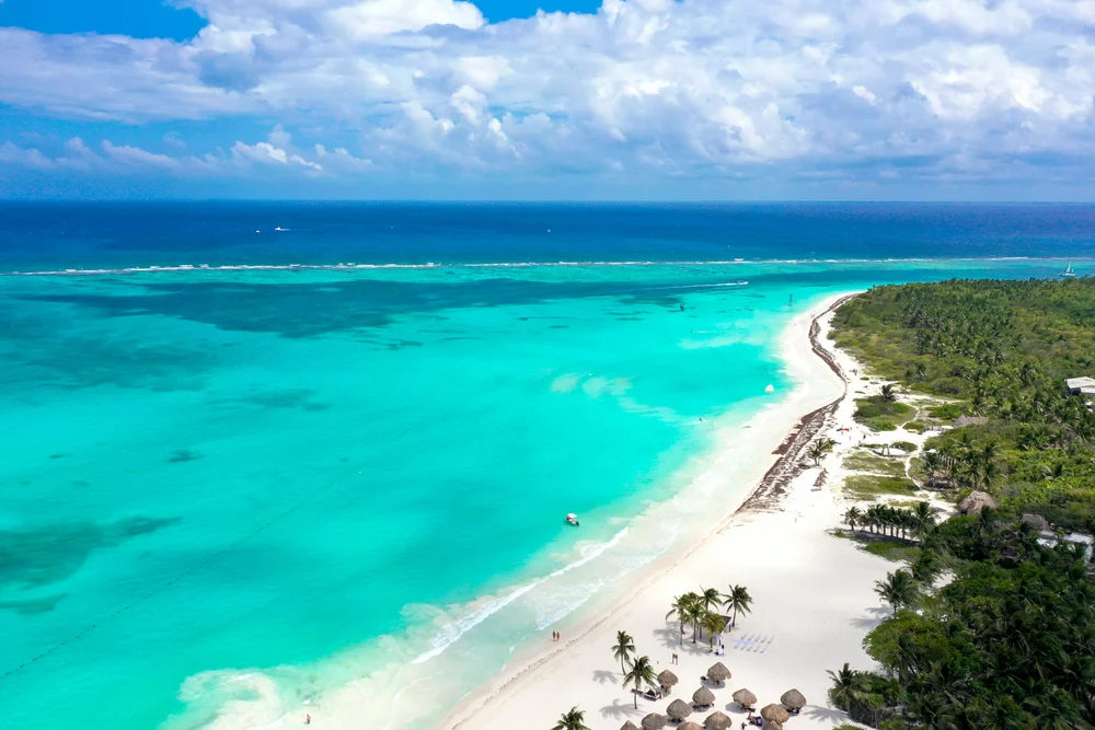 Gorgeous white sand beach pictured during the best time to visit Riviera Maya, as seen from a drone flying in the sky
