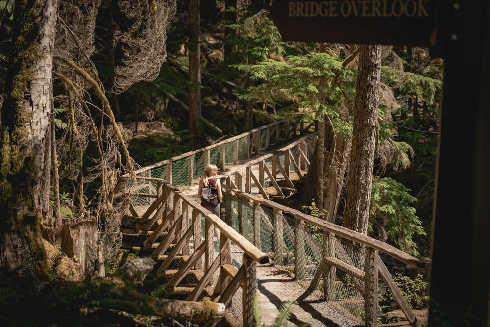 Woman walking along a bridge on the Ladder Creek Falls Trail during the best time to visit North Cascades National Park