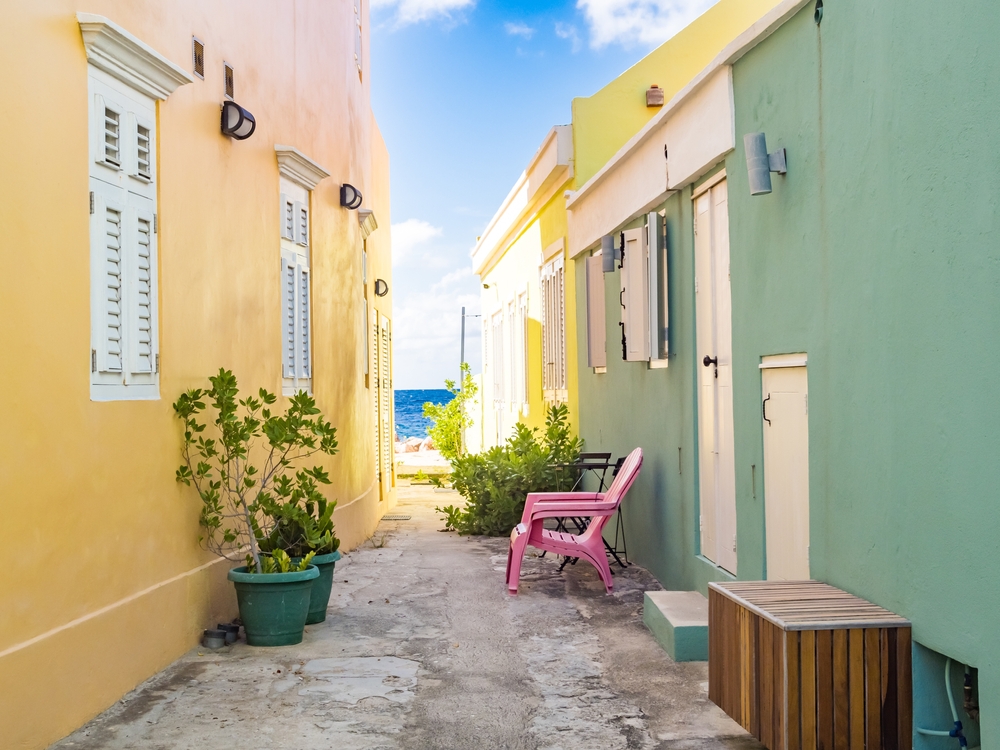 Ocean as seen from the middle of an alleyway between colorful homes during the best time to visit Curacao