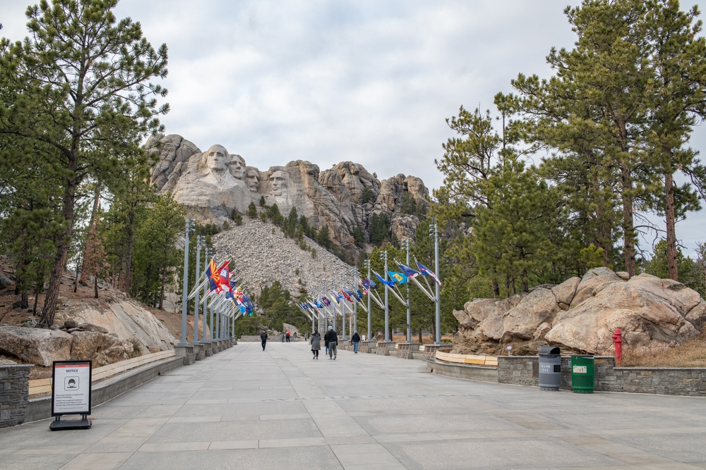 Very cold day pictured at the walkway during the least busy time to visit Mount Rushmore with few people in coats with cloudy skies above