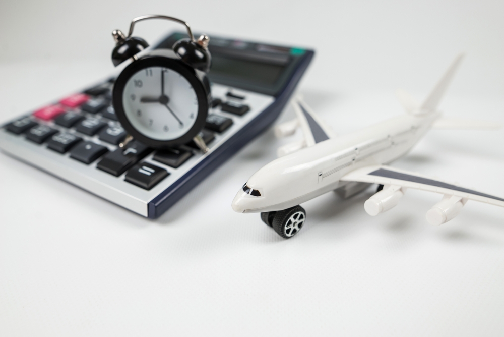 Concept image of airplane model, calculator, and clock showing the cheapest time of day to fly for a piece on the cheapest days to fly