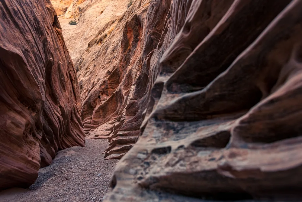 Slot canyon in Moab with huge rock faces on either side of the dry creek bed during the best time to go to Moab