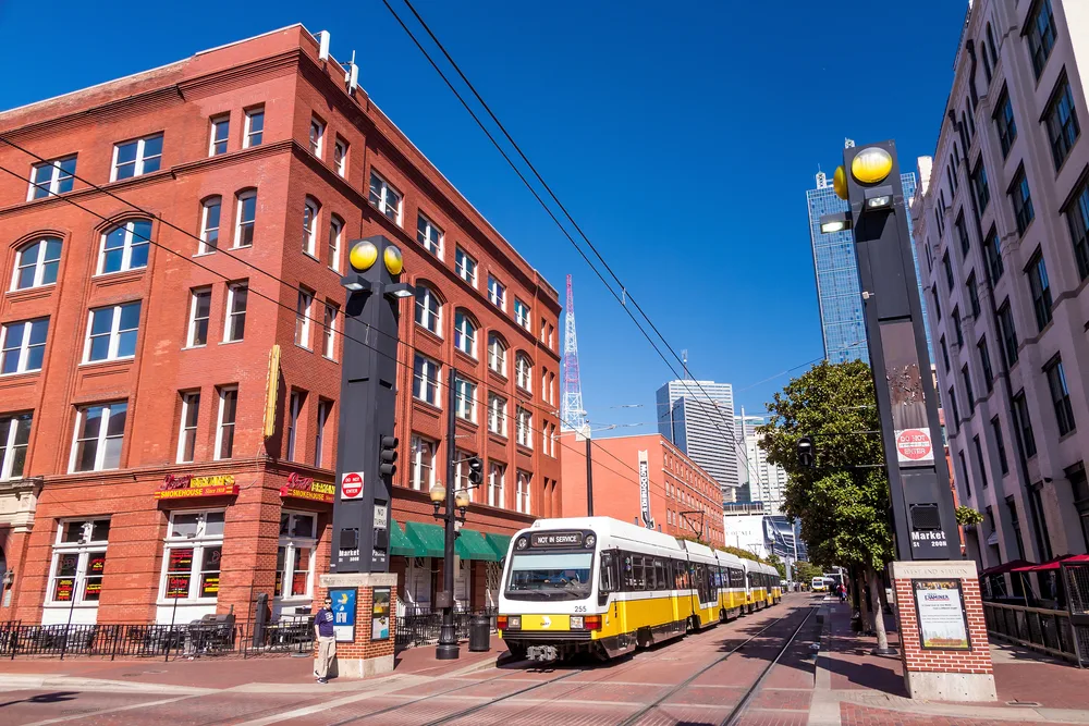 Image of a streetcar that is white and yellow in color rolling along tracks during the best time to visit Dallas