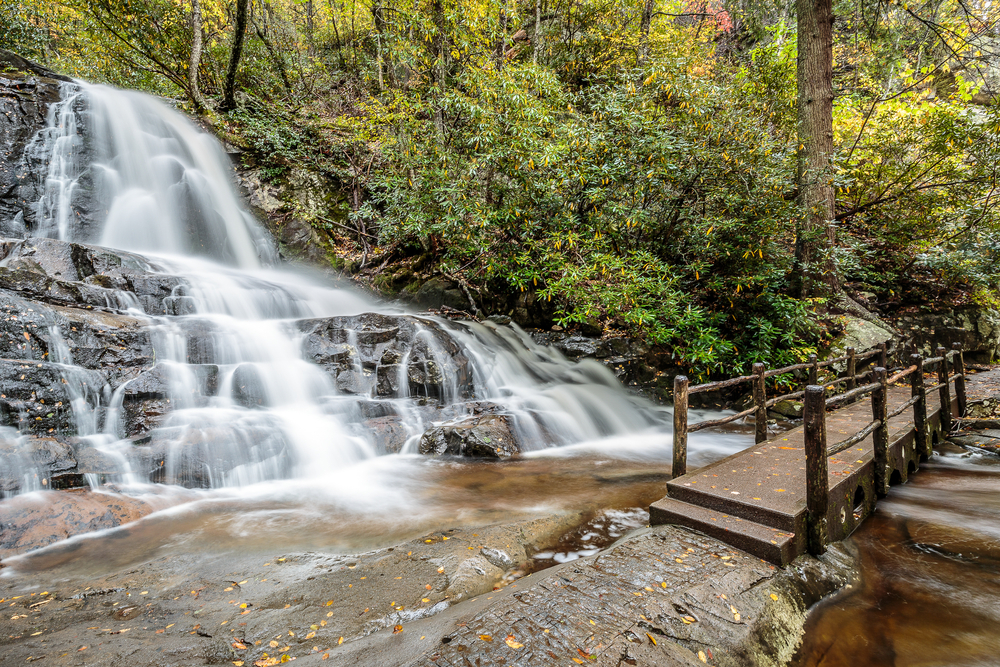 Waterfall by a bridge and a stream pictured during the cheapest time to visit Gatlinburg