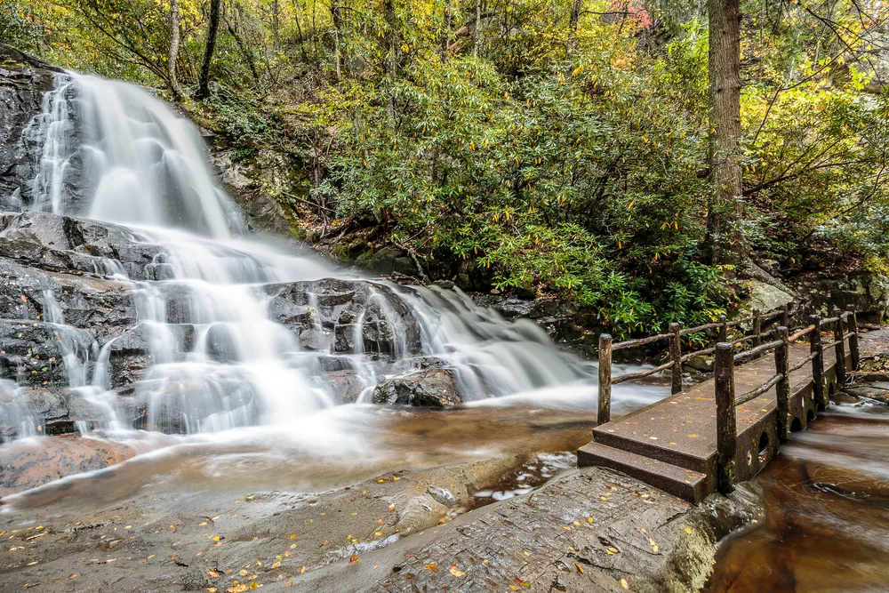 Waterfall by a bridge and a stream pictured during the cheapest time to visit Gatlinburg