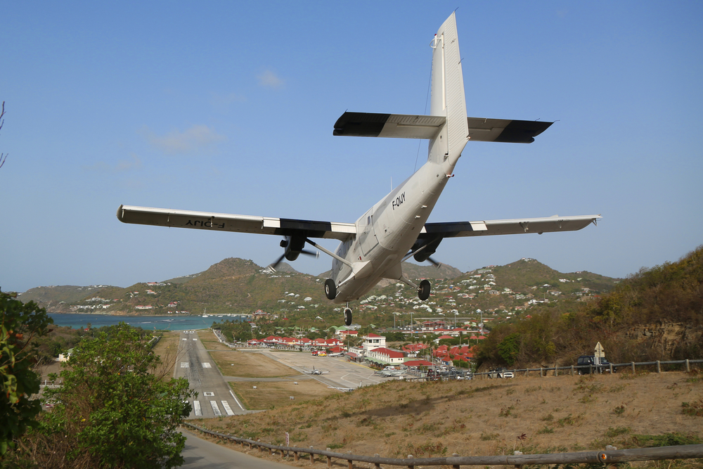 Photo of a Twin Otter coming in low over the hill in St. Barts