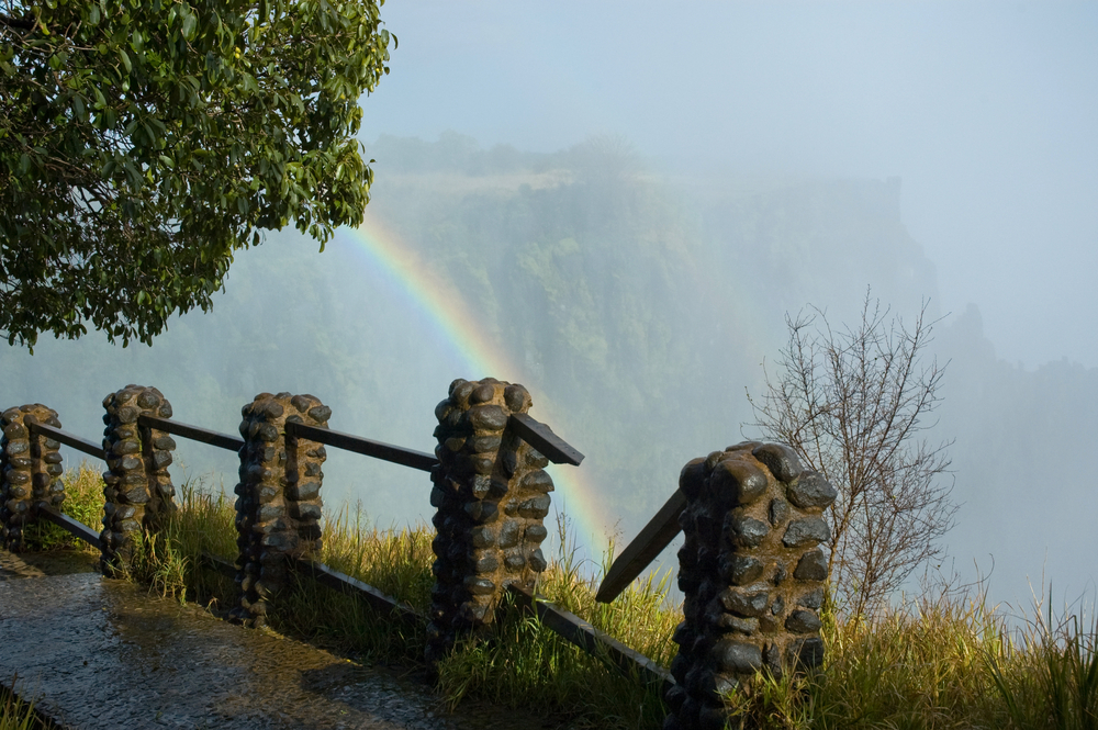 Victoria falls pictured during the worst time to visit with lots of fog, as seen from the POV of a hiker on a path