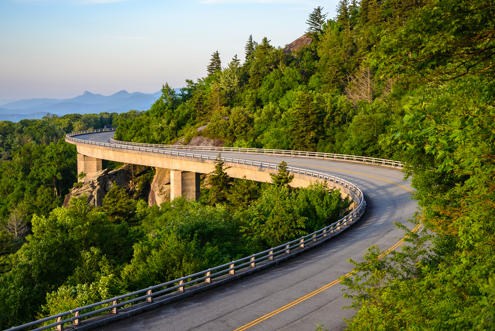 Highway winding through trees in Asheville North Carolina, one of the best places to visit in the South, on a clear day with smog on the horizon