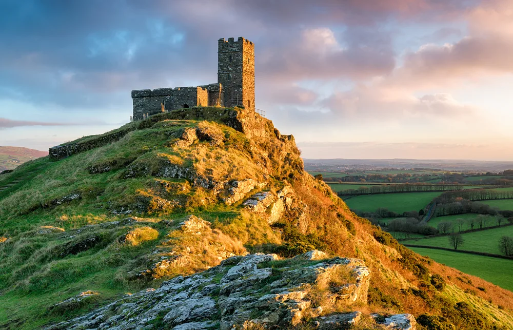 Stone castle pictured on top of a hill in Dartmoor National Park in Devon for a piece on the best places to visit in the UK