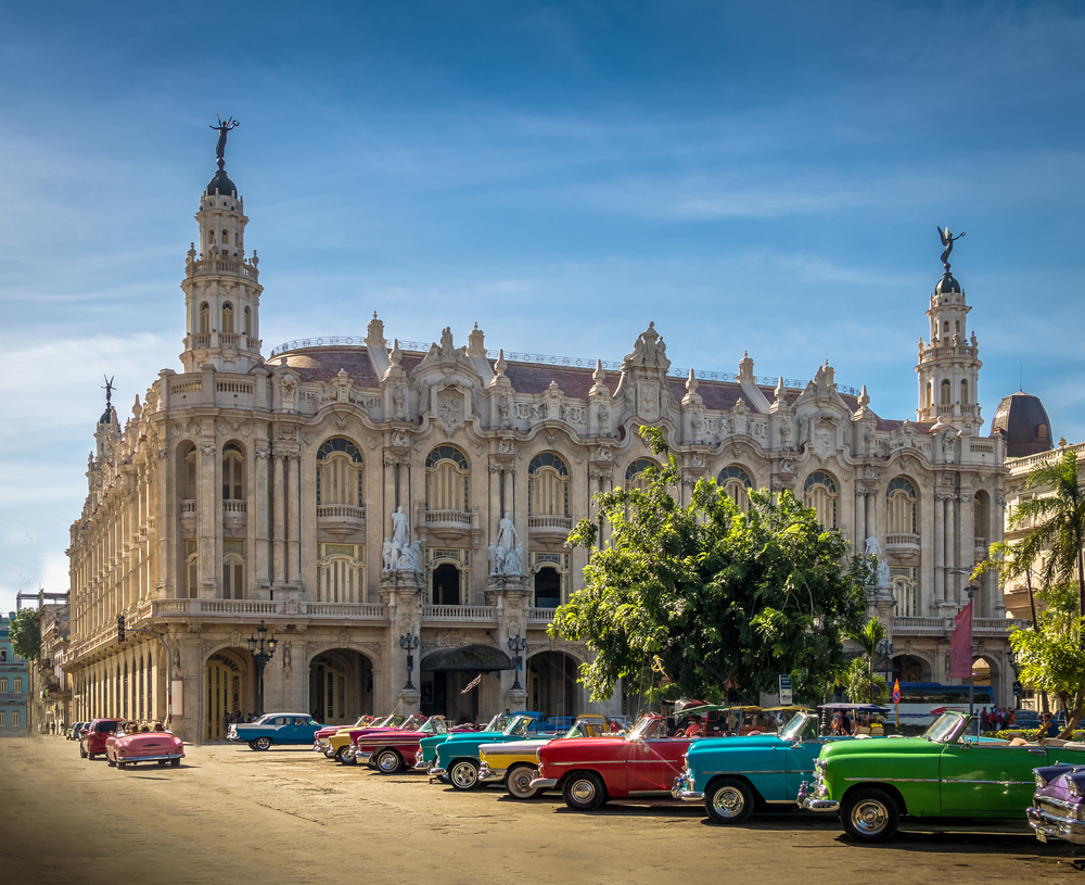 Gran Teatro in Havana pictured with bright-colored cars outside in the street for a post titled Is Cuba Safe to Visit