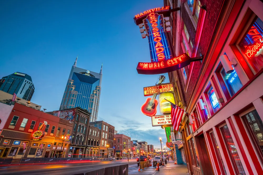 Neon signs in downtown Nashville pictured at dusk with a blue sky in the background
