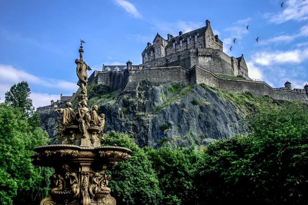 Amazing mid-day view of the Edinburgh Castle, one of the best places to visit in Scotland, as seen from the fountain in front
