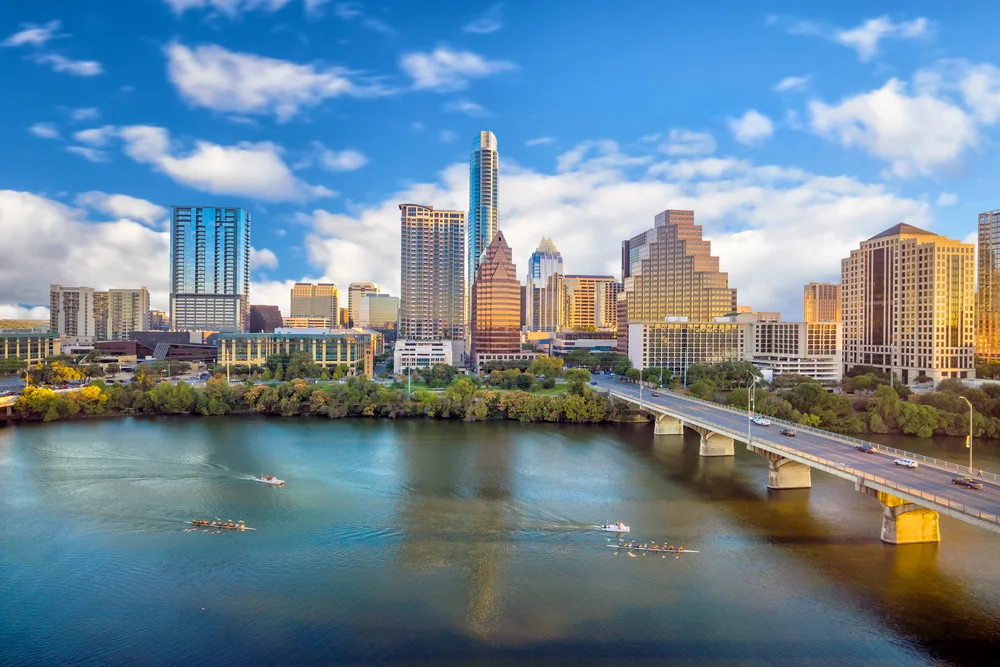 Downtown skyline of Austin, Texas, one of the top places to see in the South, pictured on a mostly sunny day with buildings overlooking the river
