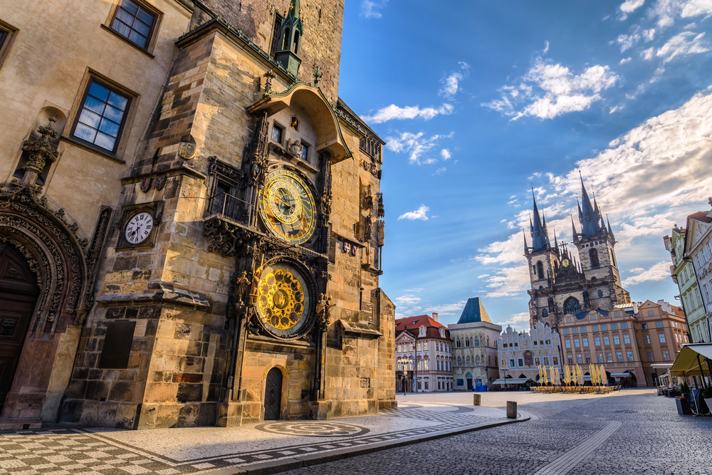 Neat view of the Old Town Square and cathedral pictured on a day when nobody is around and only a few clouds are in the sky for a piece titled Is Prague Safe to Visit