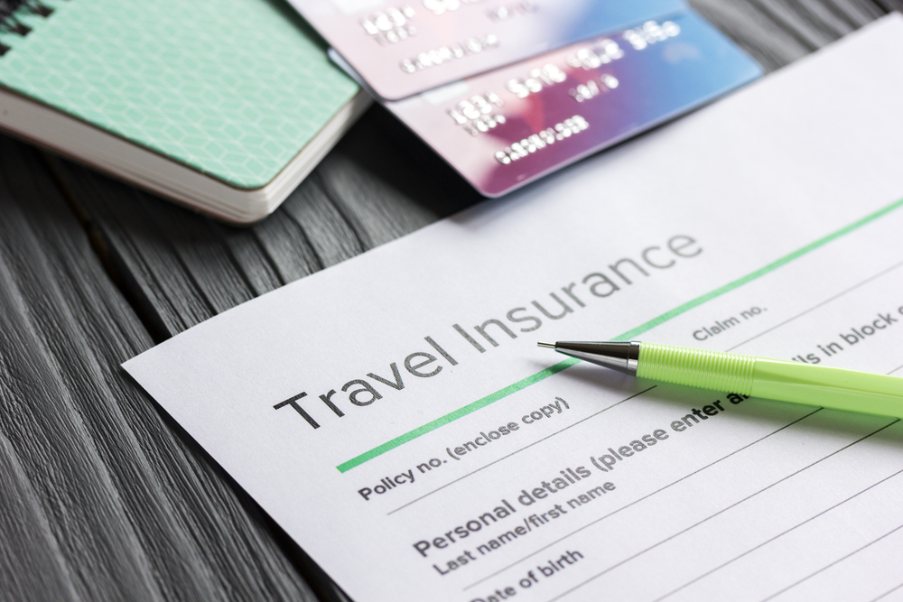 Travel insurance form with pen, credit cards, and passport for a piece on the best travel insurance plans