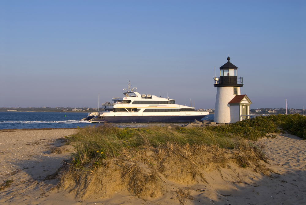 Ferry passing alongside a lighthouse during the late spring, the best time to take a trip to Nantucket