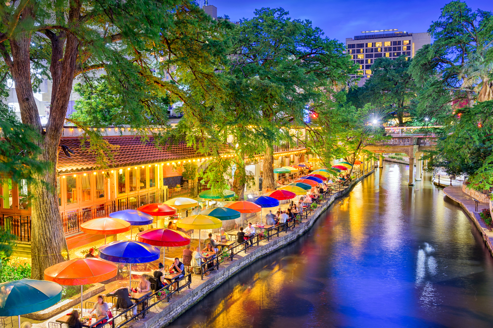 Dusk view of the San Antonio riverfront with colorful umbrellas on the patio for roundup of the best places to visit in Texas