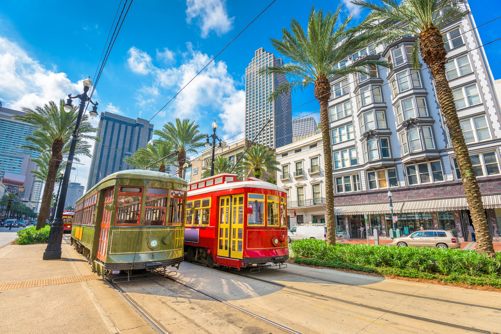 Red street cars moving along their tracks in New Orleans, one of the best places to visit in the South